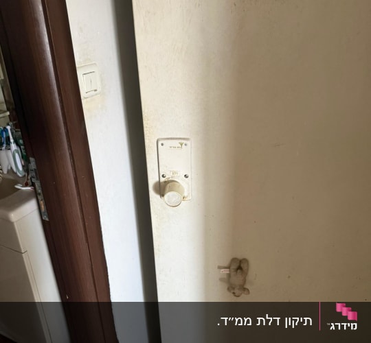 דלת ממ"ד לבנה עם מנגנון נעילה וידית מסתובבת